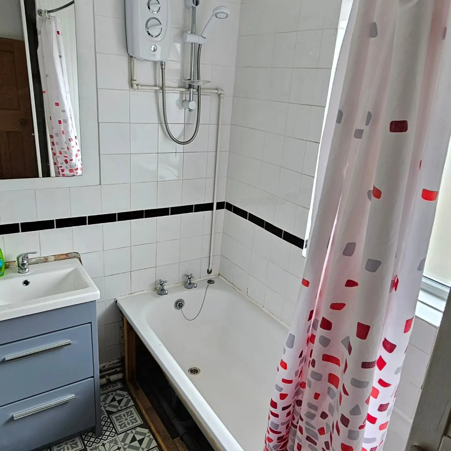 A bathroom with a bathtub, sink, and mirror.