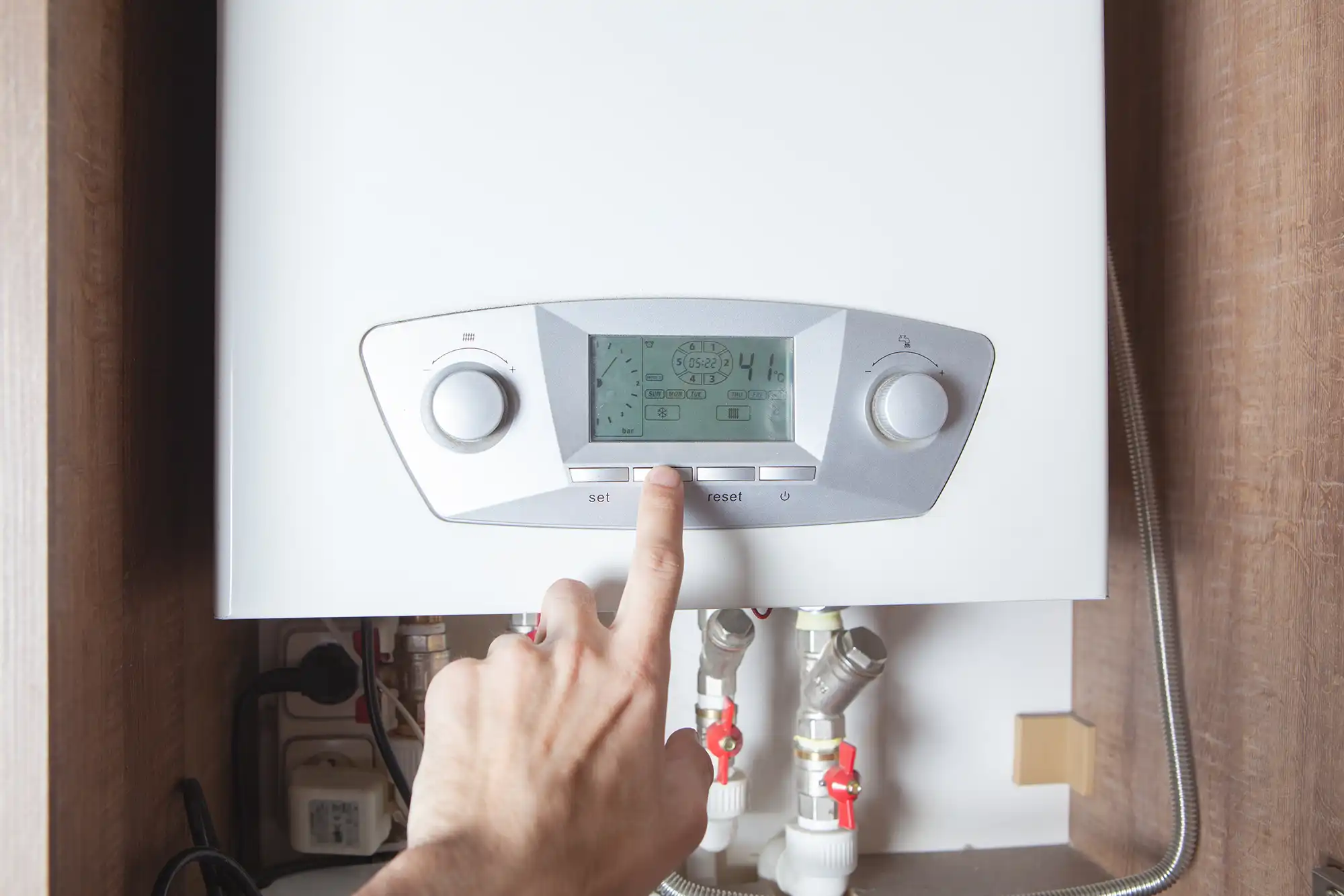 A person pointing at a boiler on a wall.