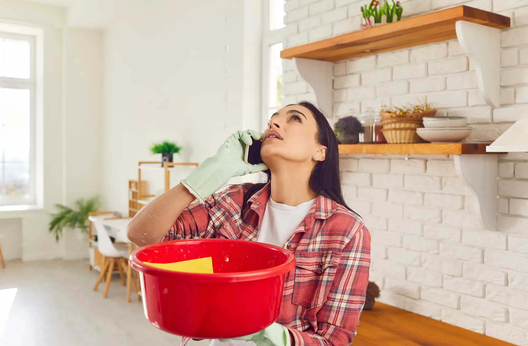 A woman with a bucket under a leaking ceiling.