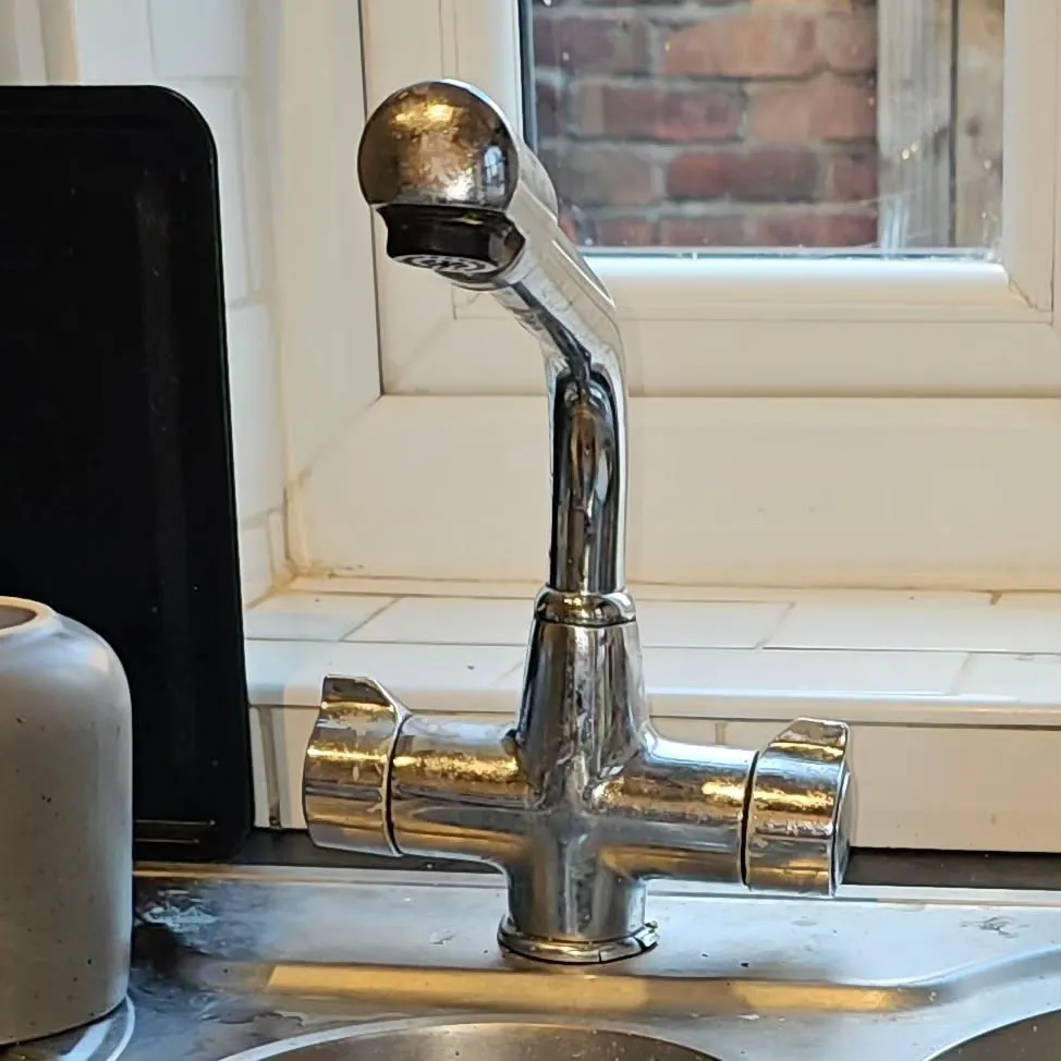 A kitchen sink with a faucet running from the faucet.