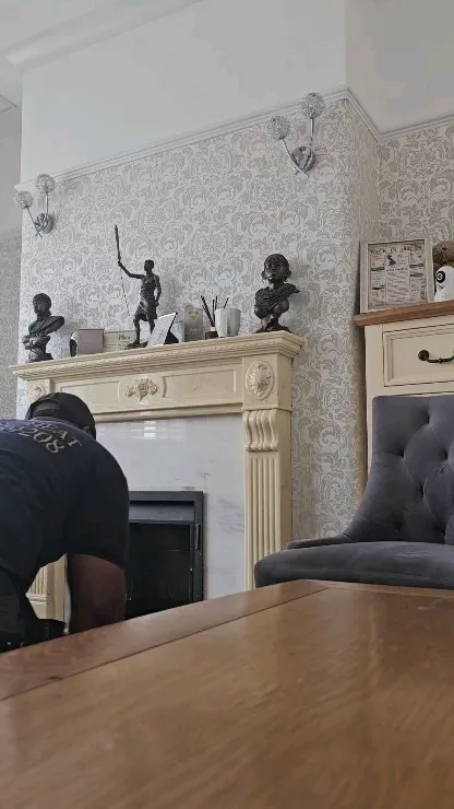 A man working on a fireplace in a living room.