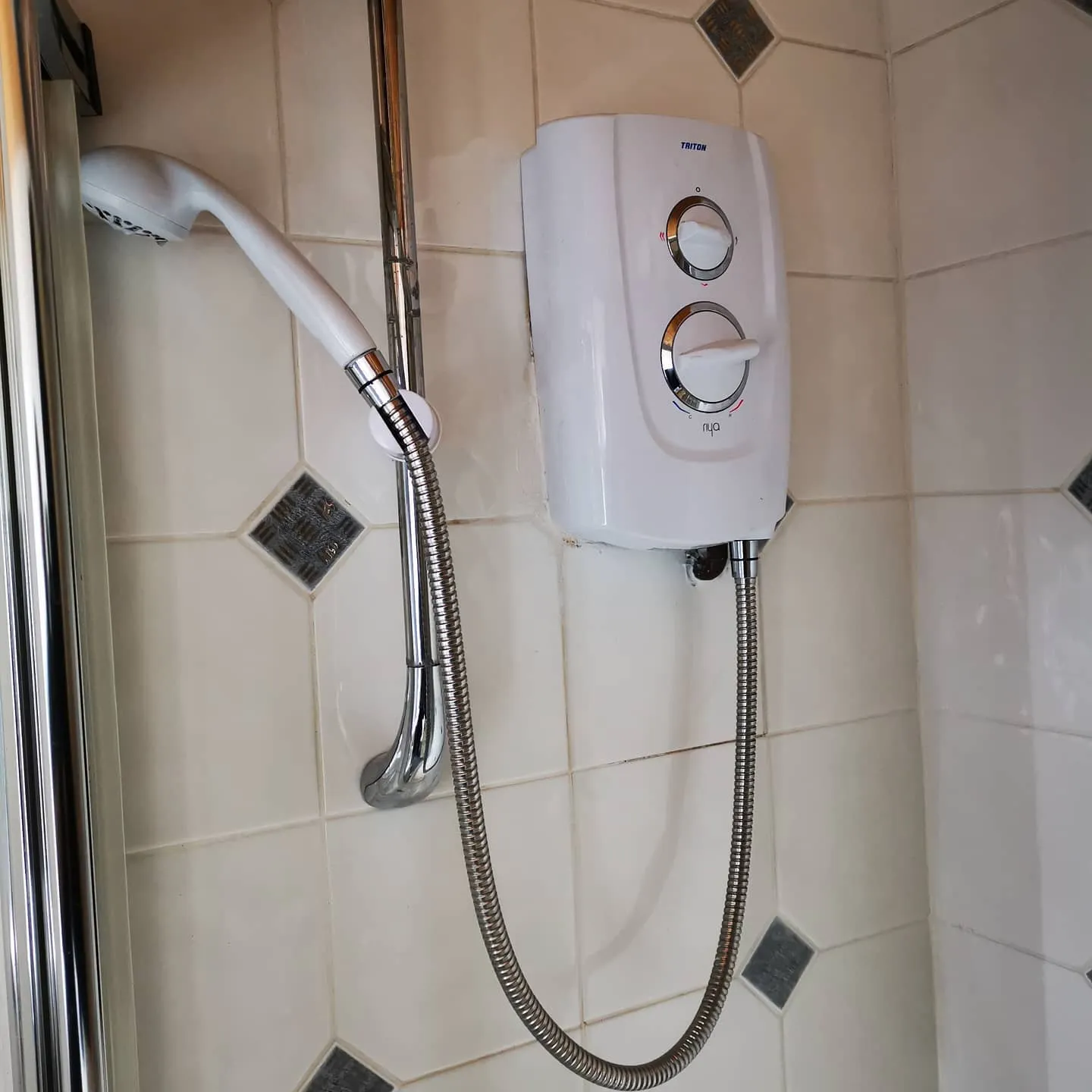 A shower head mounted to a tiled wall.