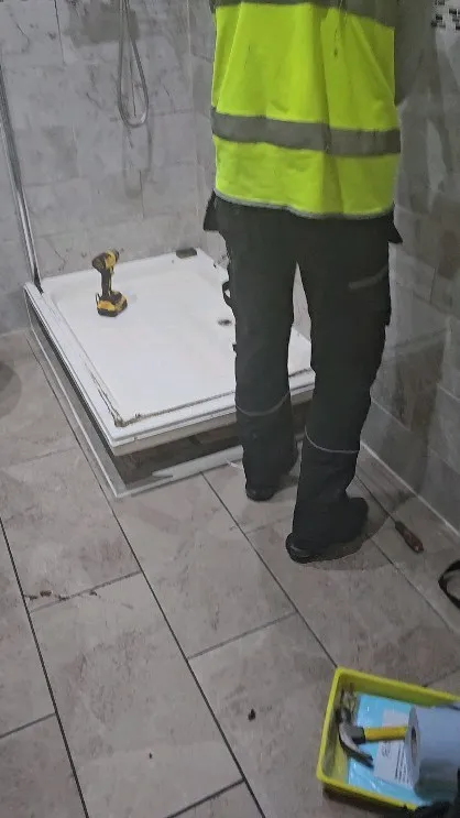 A man in a yellow safety vest standing in front of a shower.