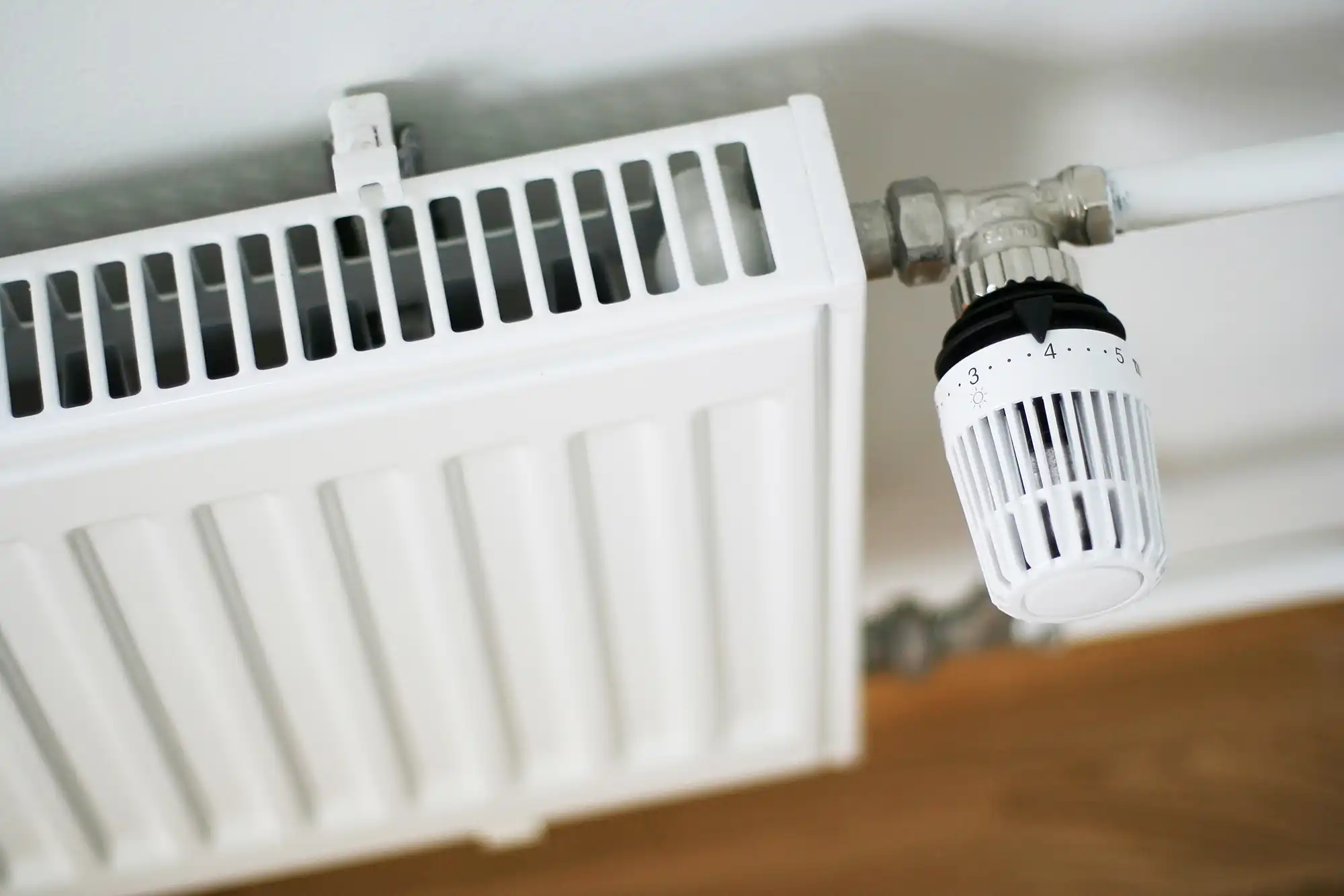 A white radiator sitting on top of a wooden floor.